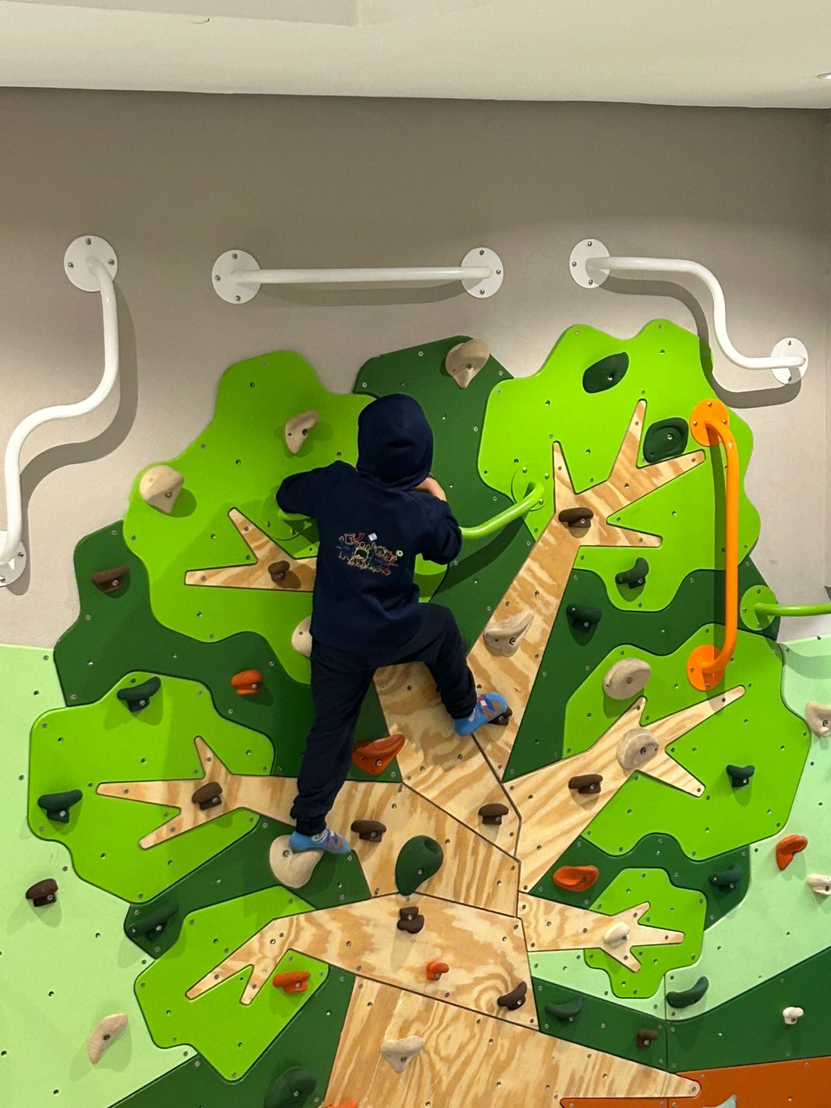 Criança explorando percurso de escalada em brinquedoteca, estimulando coordenação e desenvolvimento infantil